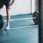 man in black t-shirt and black shorts holding black barbell